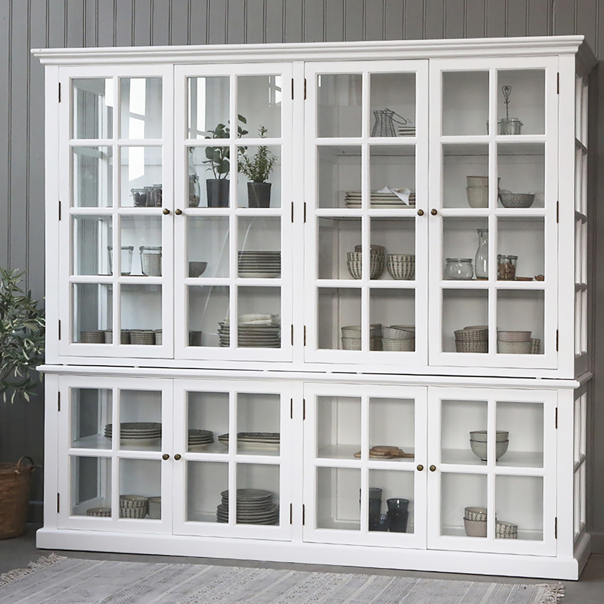 Large white armoire cabinet with glass doors filled with kitchen crockery.
