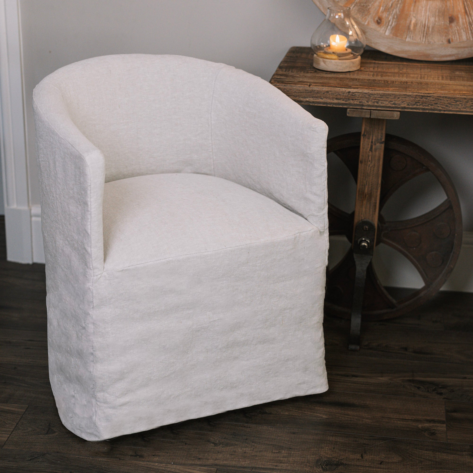 Natural linen dining chair with rounded back on wooden floor next to wooden table.