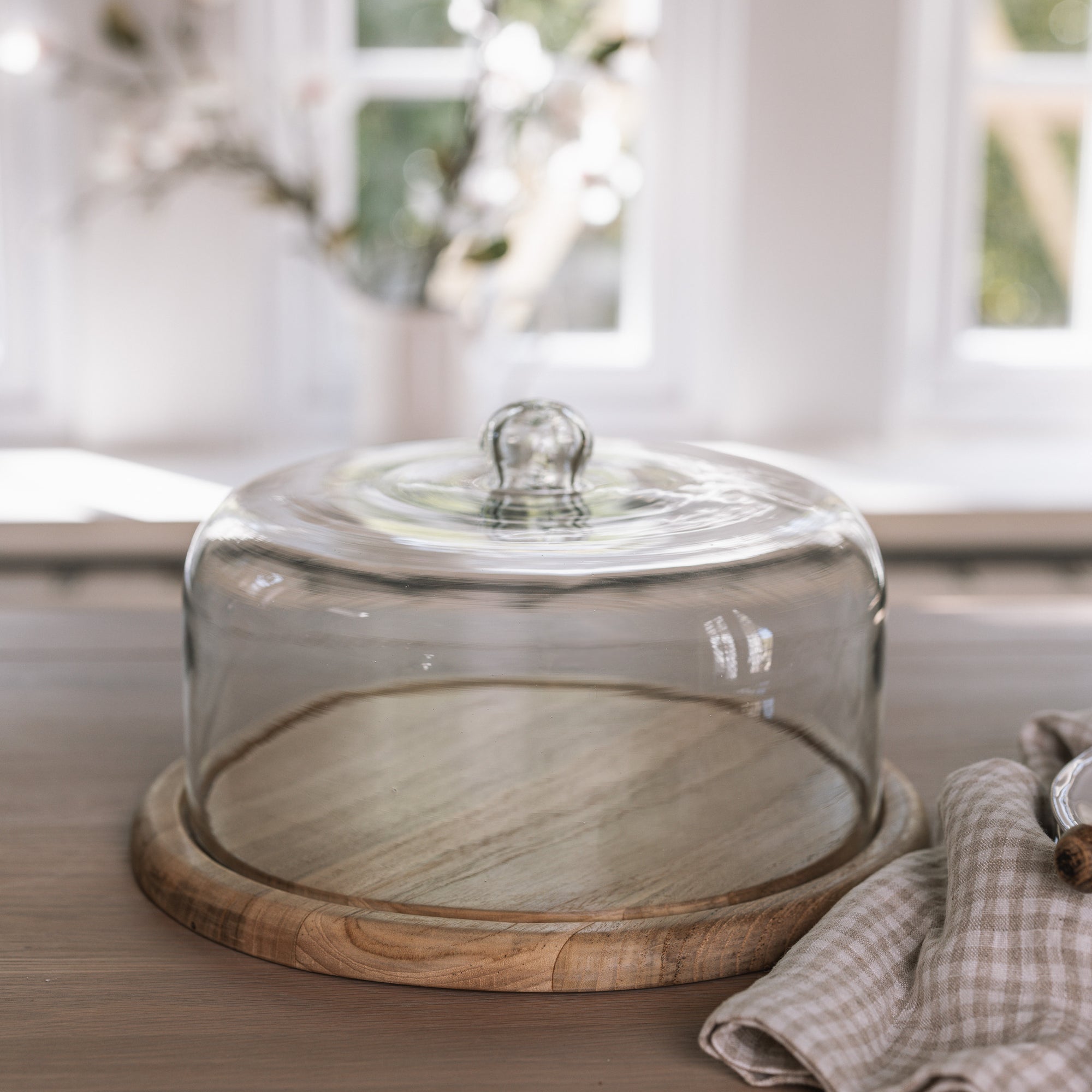 Recycled Glass Cake Dome with wooden base on wooden tale with gingham tea towel.