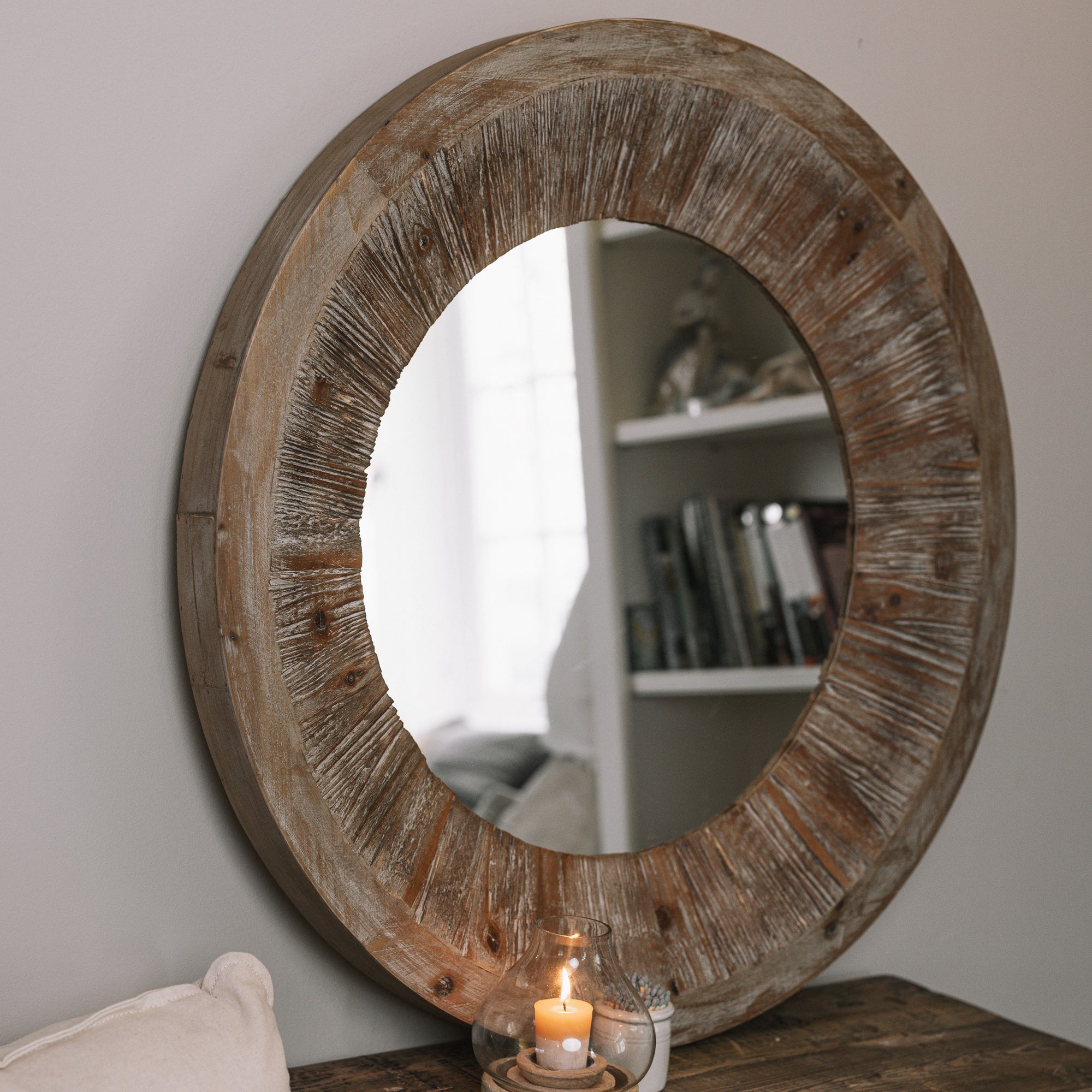 Rustic Round Wooden Mirror on wooden table with small candle and pot of matches.