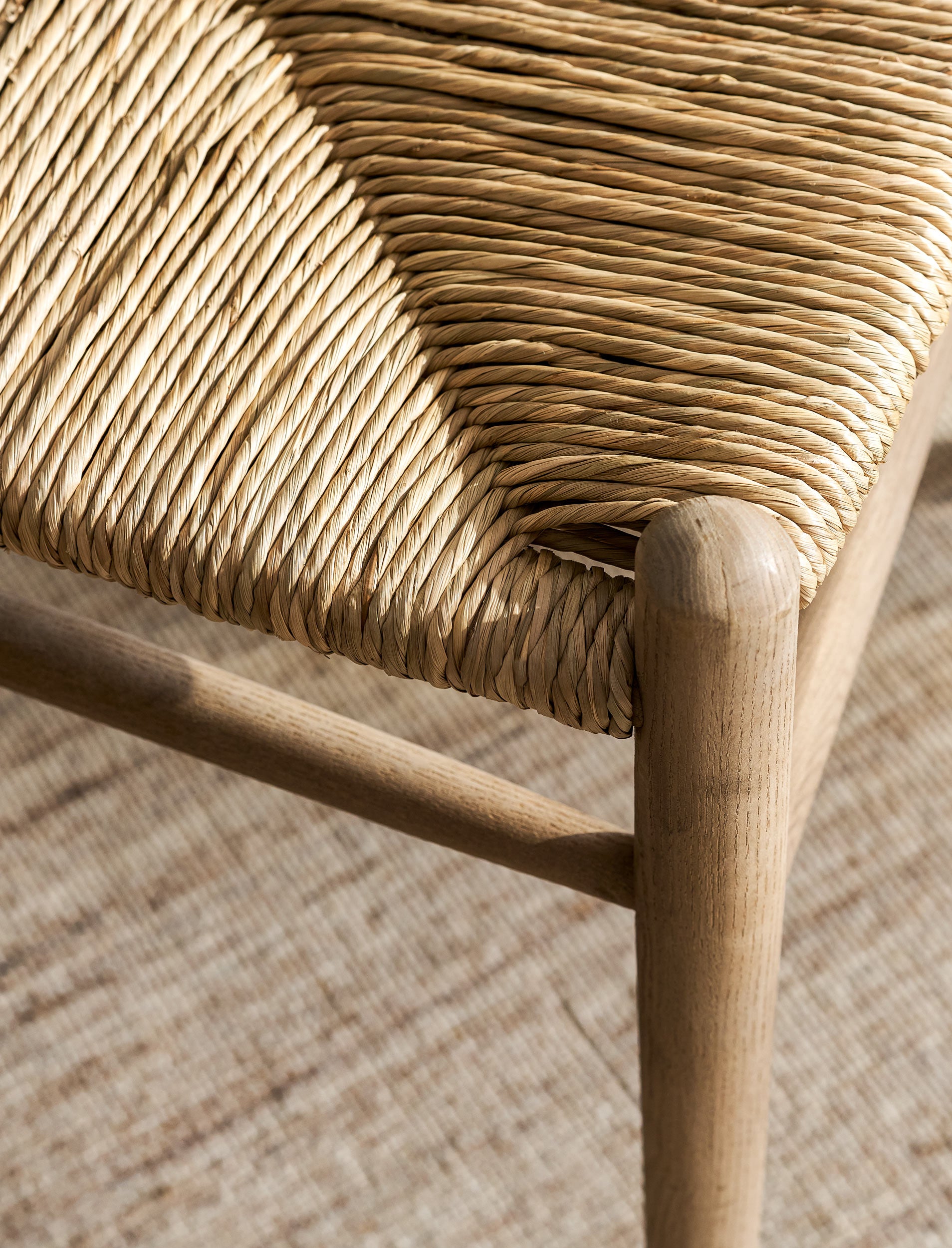 Close-up of a wicker wishbone dining chairs with wooden frame on a textured surface