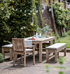 Outdoor dining table with chairs and benches, and crockery on top.