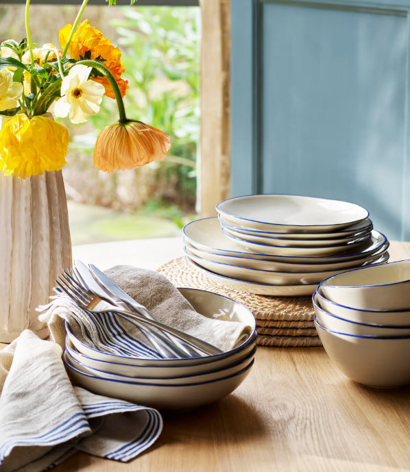 Blue and white stoneware side plates with full dinnerware set and cutlery on table.