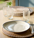 Blue and white stoneware dinner plates on dining table with cutlery and glasses.