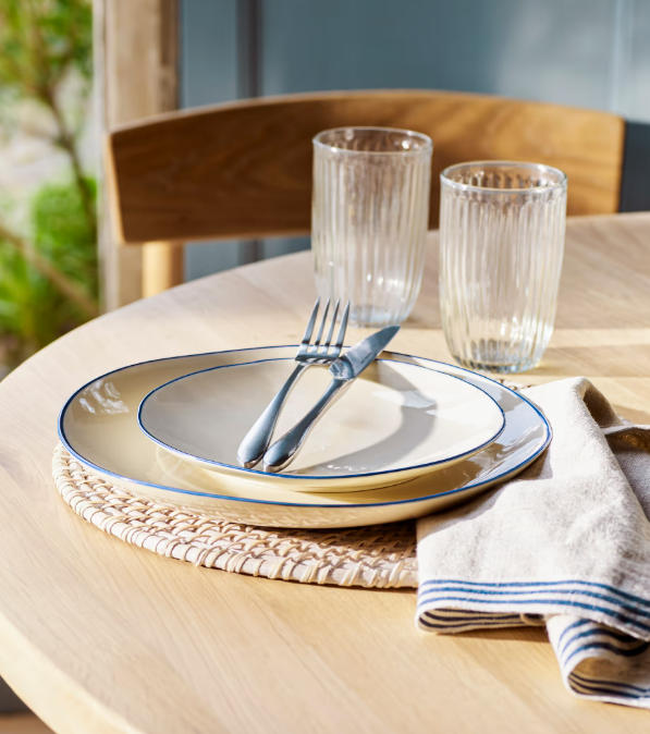 Blue and white stoneware side plates with dinner plates and cutlery on table.