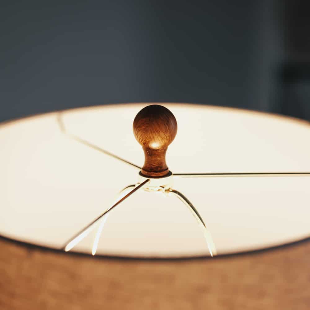 Close up of lamp shade switched on with wooden top.