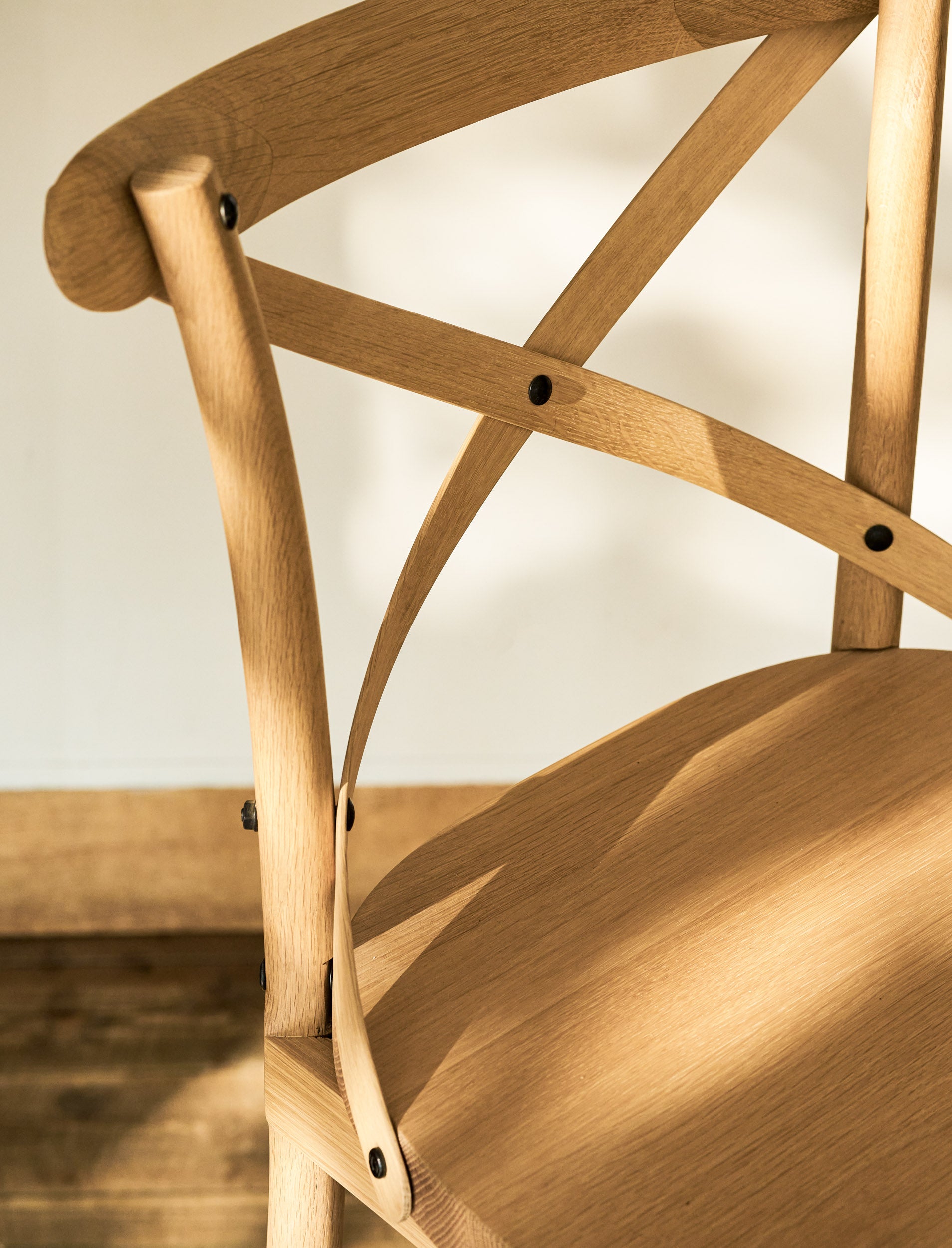 Close-up of a wooden chair with a cross-back design on a neutral background