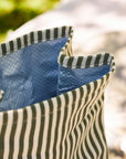 Close-up of a blue and green striped lunch bag with a blurred natural background