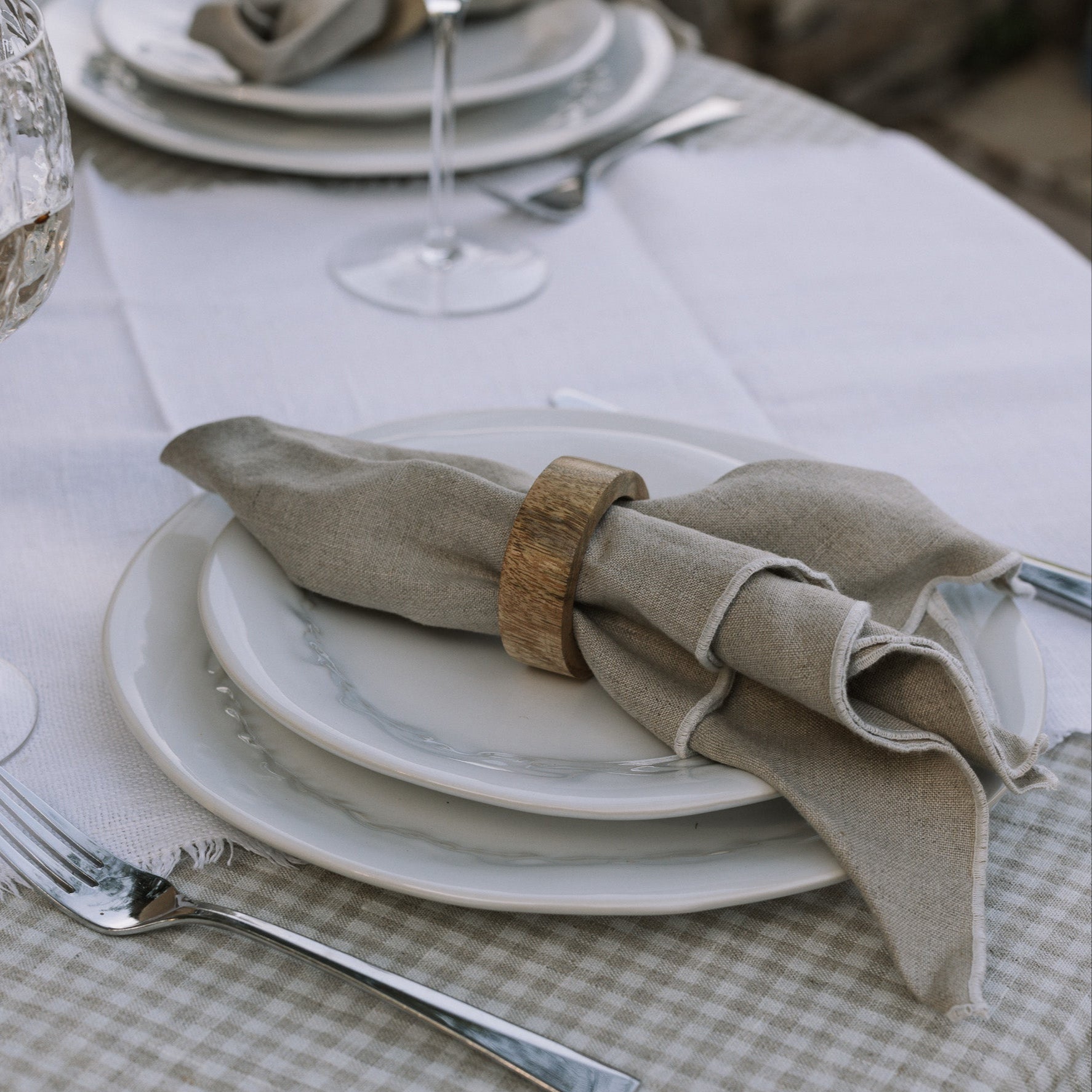 wooden napkin ring on beige linen napkin on gingham table cloth.