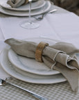 wooden napkin ring on beige linen napkin on gingham table cloth.