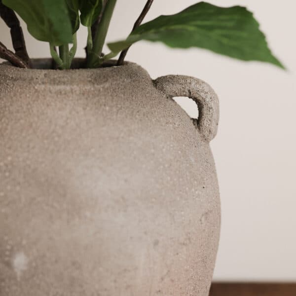 a rustic grey vase against a white wall.