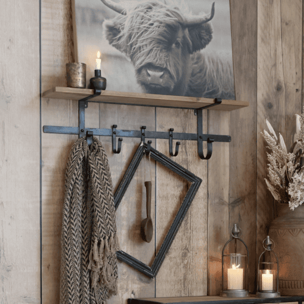rustic metal shelf with a painting of a cow and candle decor.