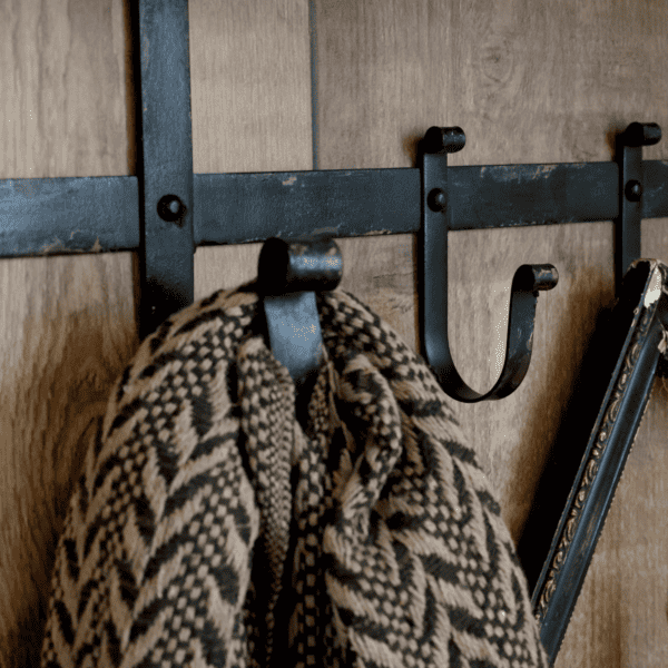 rustic metal hook holding a scarf against a metal wall
