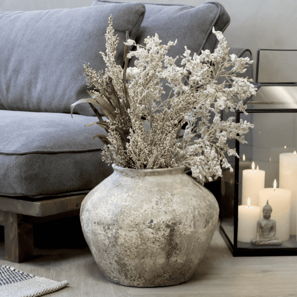 Stoneware vase by a blue sofa with dried flowers