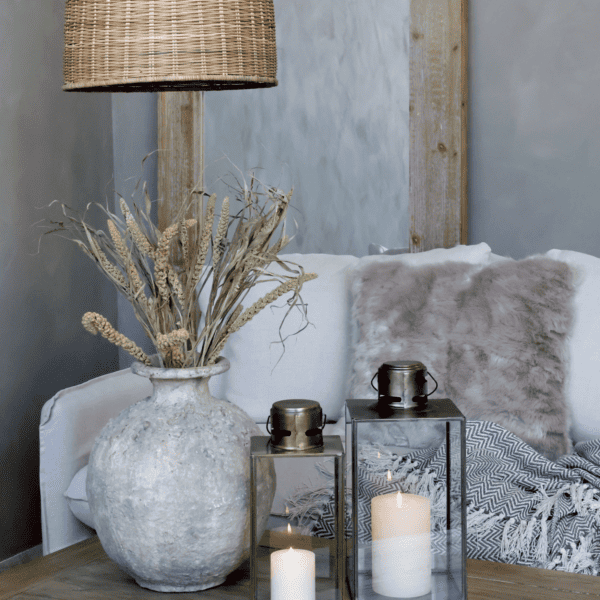 Living room scene with a rustic vase and two lanterns on a coffee table.