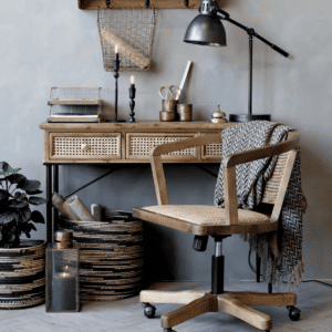 Wooden office chair at a wood and cane desk with a lamp.
