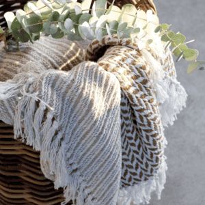 Chic Antique Striped Throw in Latte in a basket with eucalyptus.