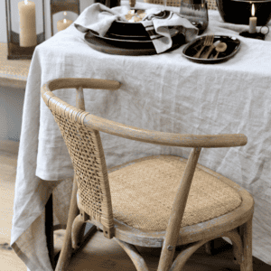 Wooden dining chair with wicker back at dining table with linen table cloth