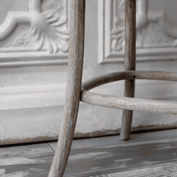 white washed bar stool leg at carved bar.