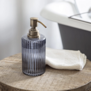 Nkuku Valeska Recycled Glass Soap Dispenser On Table With Wash Cloth