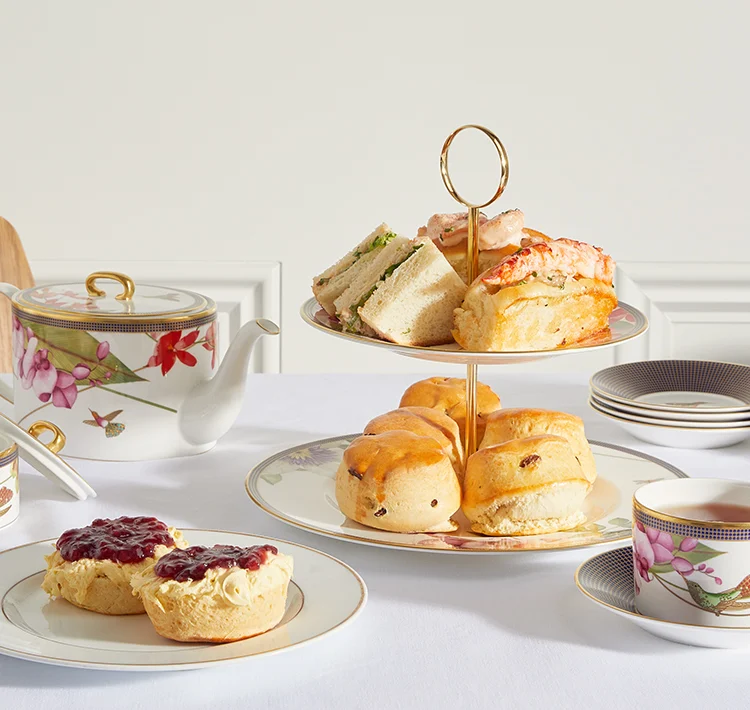 Afternoon tea at home with cake stand and cakes on white plates.