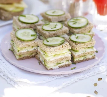 Savoury afternoon tea cucumber and herb sandwiches on pink plate.