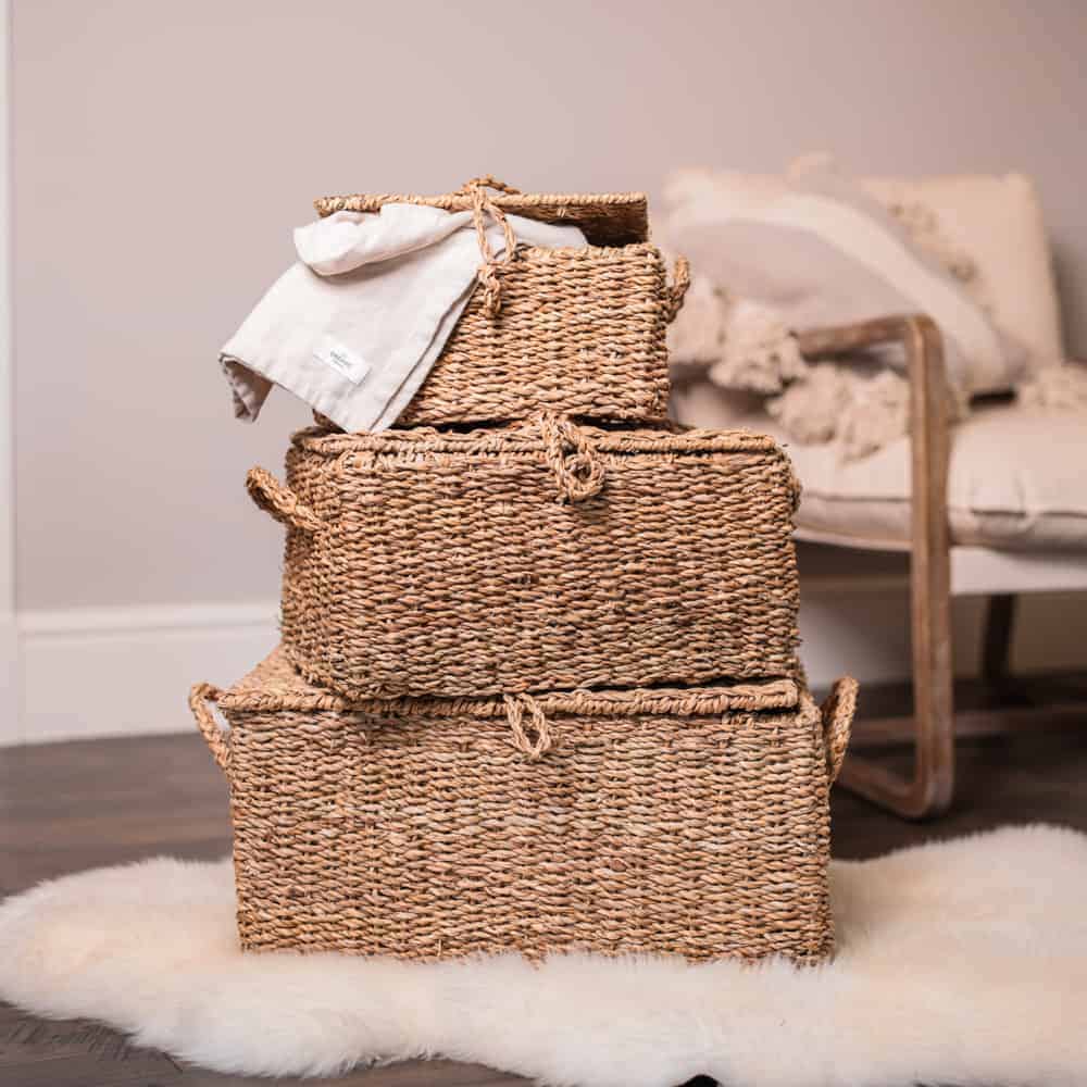 3 woven storage trunks in a stack on a furry rug.