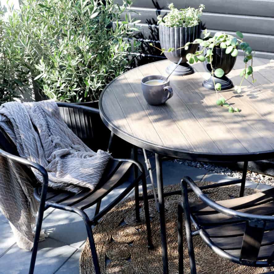 Bistro set outdoor seating area with coffee and cosy throw.