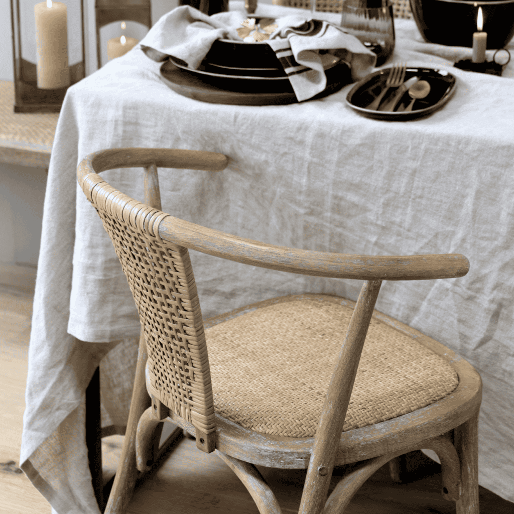Rattan wicker dining chair, at table with white linens.